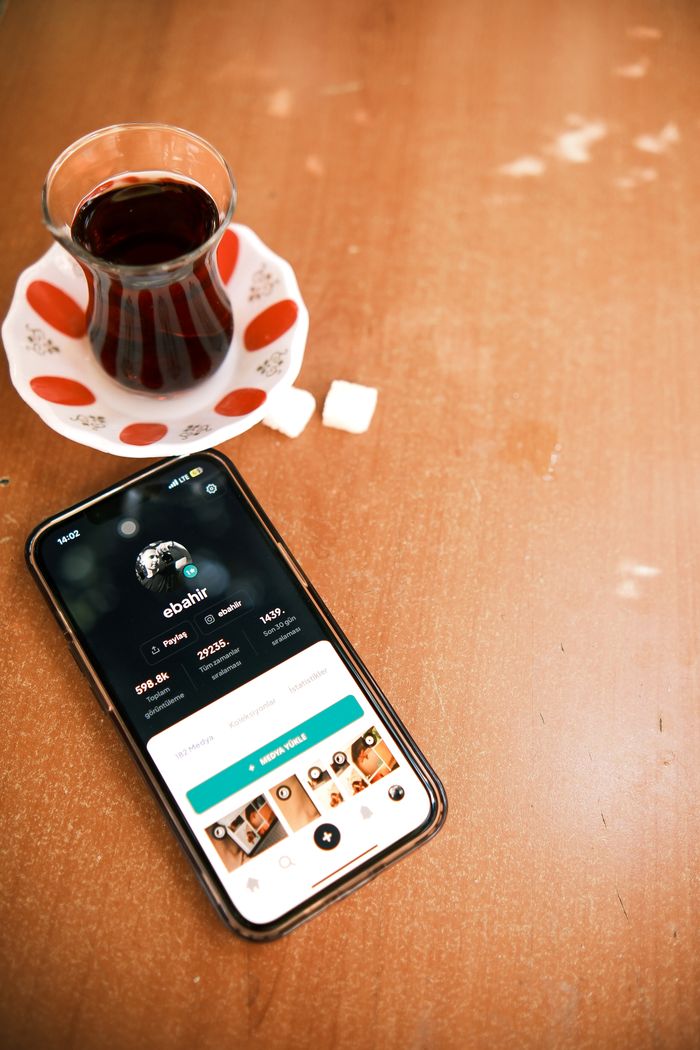 Services Close-up of smartphone with social media app next to Turkish tea and sugar cubes.