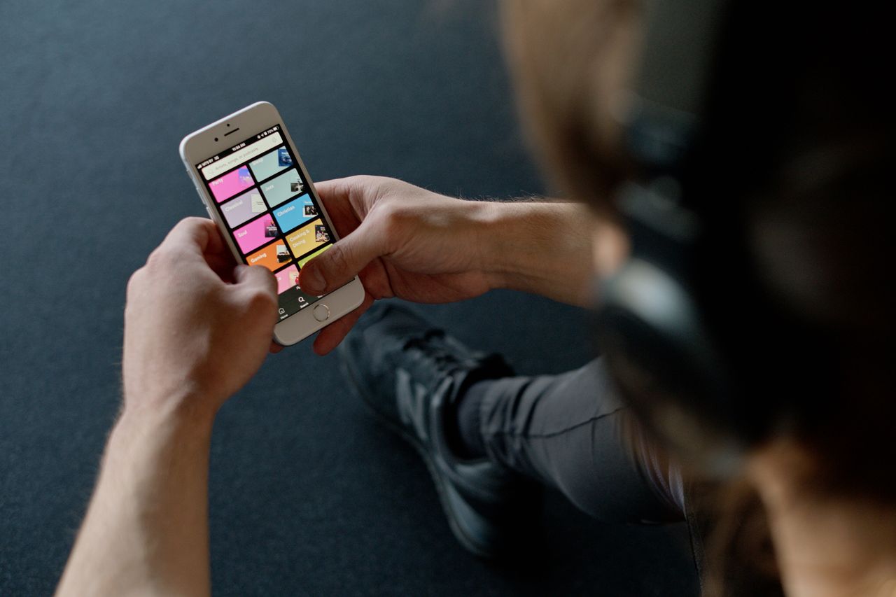 Services Close-up of a person listening to music on a smartphone while at the gym, focusing on a streaming playlist app.