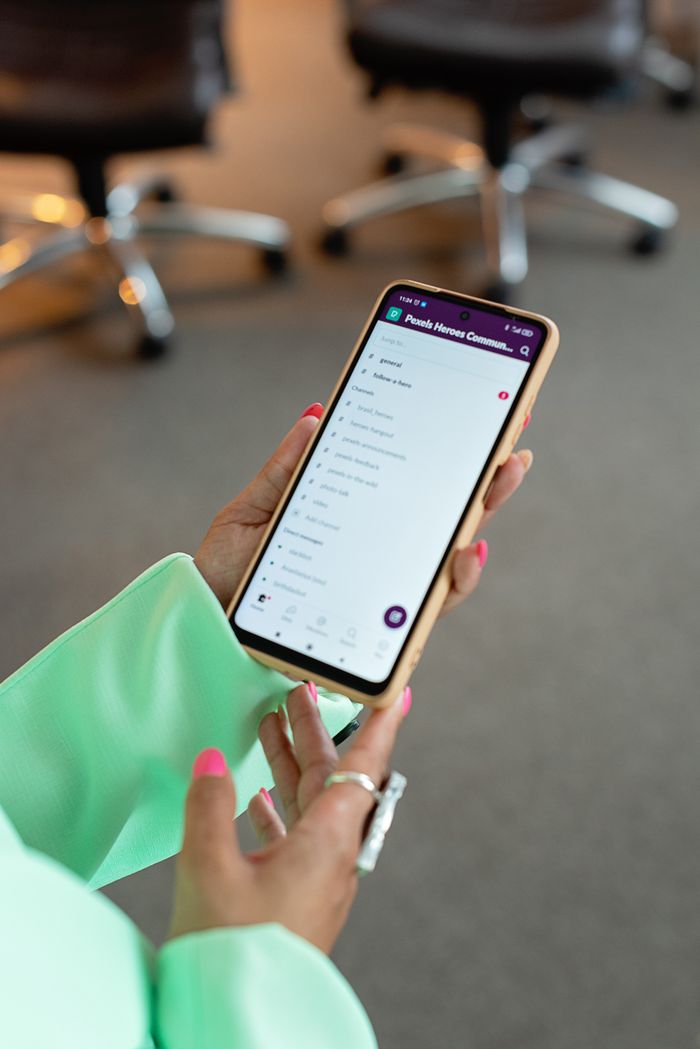 About Elegant hands holding smartphone displaying app screen in modern office environment.